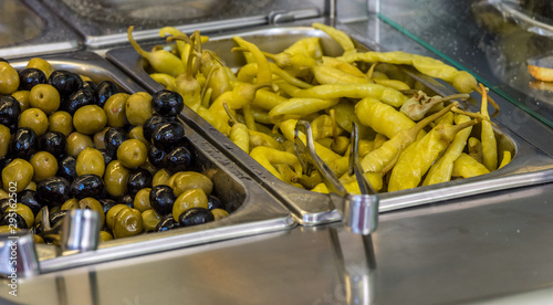 ingredients at a falafel bar with metal vegetable tongs green peppers black olives green olives and cabbage