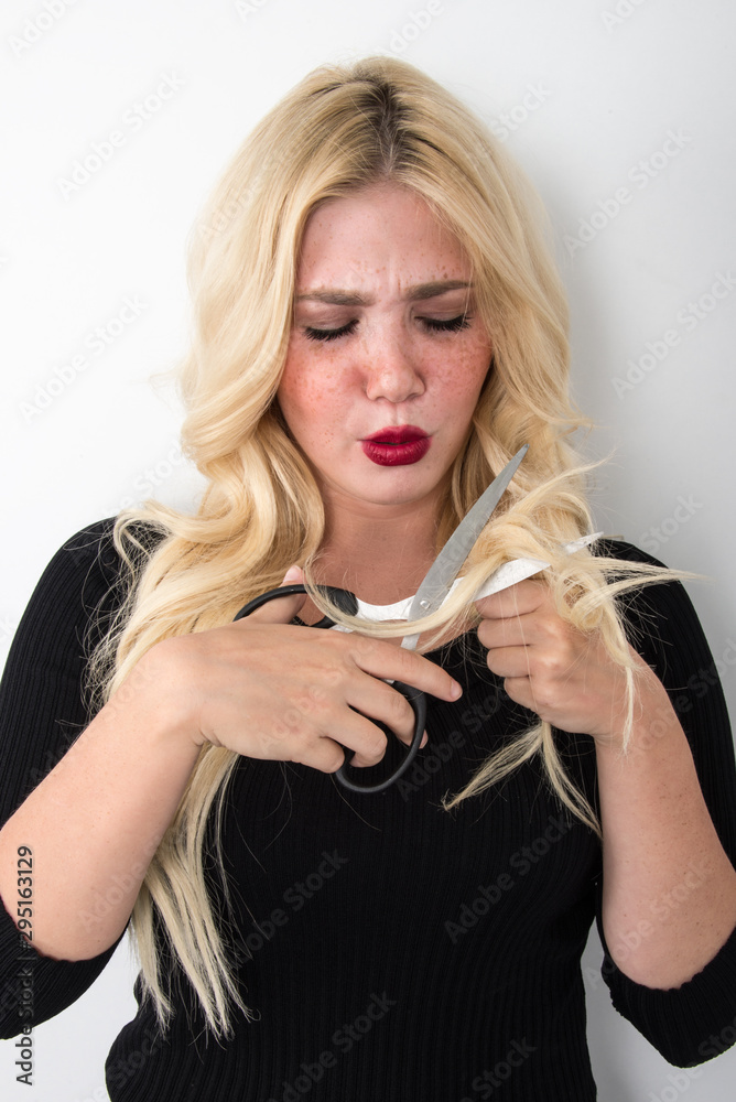 Naklejka premium Blond young woman hair problems, girl with blue eyes and freckle holding magnifier and scissor unhappy dry and damaged hair concept hair care