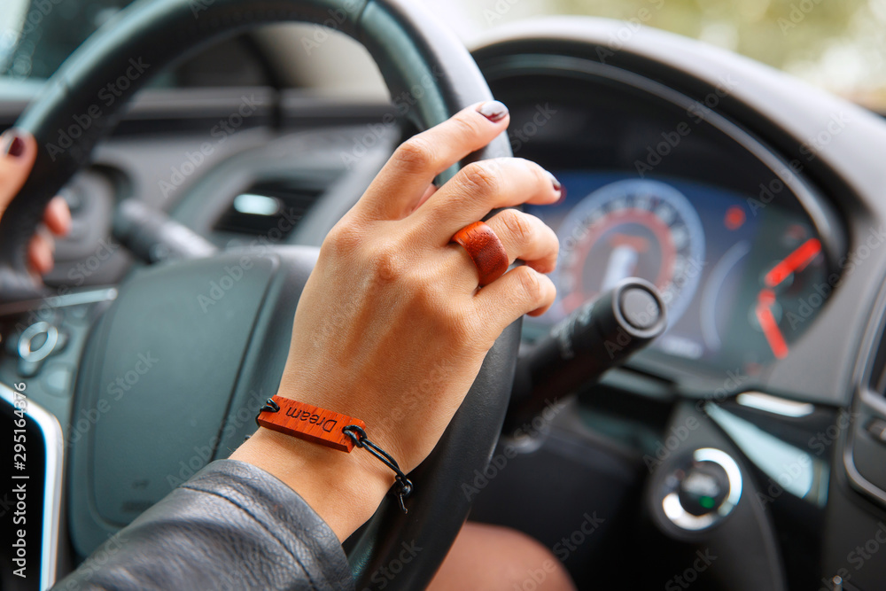 Shooting concept: girl s hands on the steering wheel of a car, a bracelet with the inscription dream on her hand.