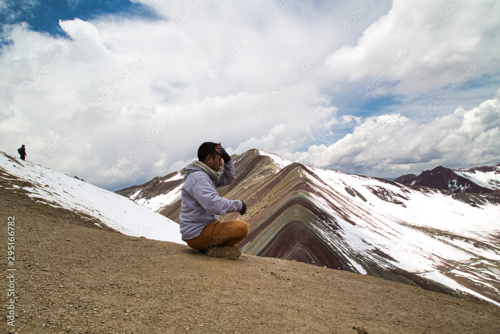 Fototapeta premium Mężczyzna medytuje z panoramicznym widokiem. Scena pieszych wędrówek w Vinicunca, region Cusco, Peru. Montana of Seven Colours, Rainbow Mountain.