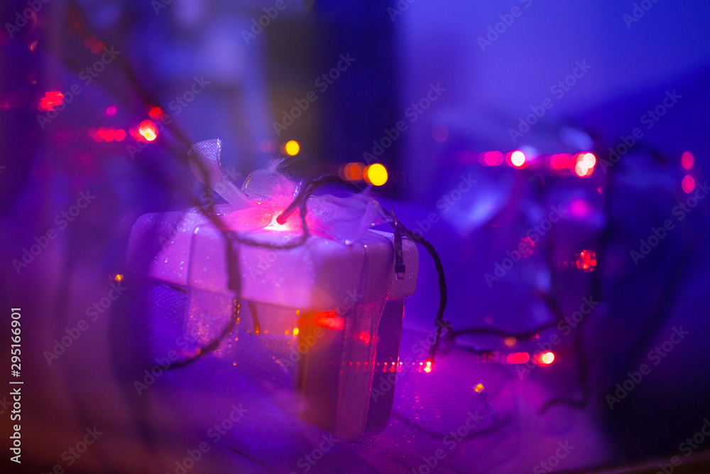 small christmas present box in violet-blue light of garlands small christmas present box in violet-blue light of garlands