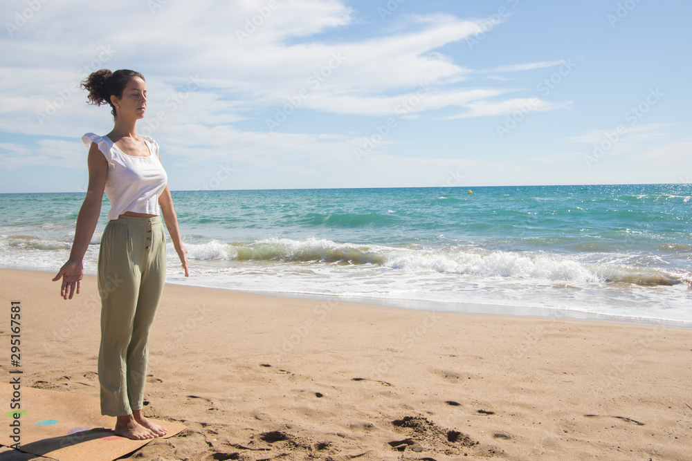 Yoga teacher doing some yoga exercises by the beach. Morning routine.