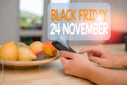 Word writing text Black Friday 24 November. Business photo showcasing Special sales Thanksgiving discounts Clearance woman using smartphone office supplies technological devices inside home photo