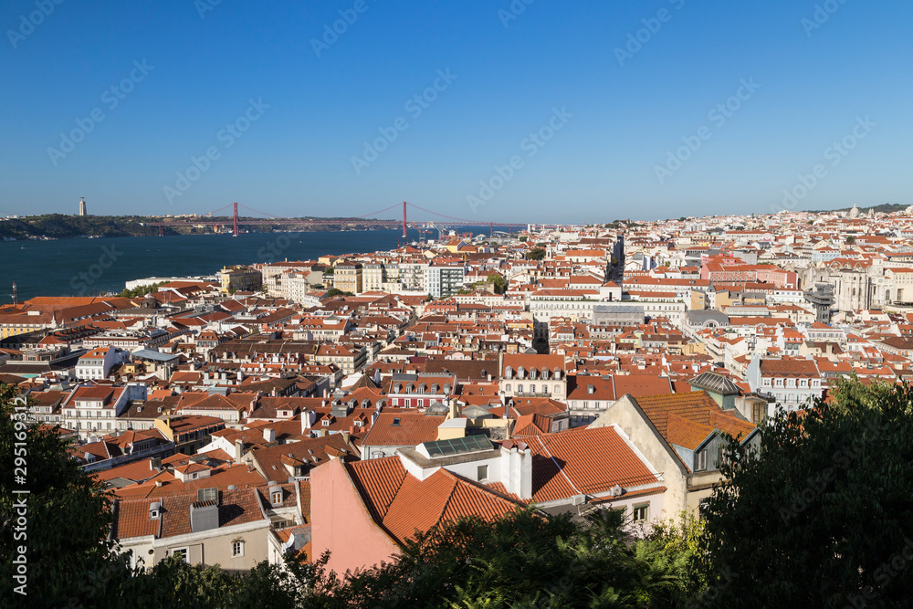View of the historical Alfama district in Lisbon, Portugal and beyond from above. Tagus River, 25 de Abril Bridge and Sanctuary of Christ the King (Santuario de Cristo Rei) monument are on background.