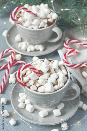 Mugs filled with hot chocolate and marshmallows and candy cane