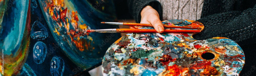 Modern fine art school. Female painter holding colorful palette and paintbrushes over abstract artwork. - obrazy, fototapety, plakaty 