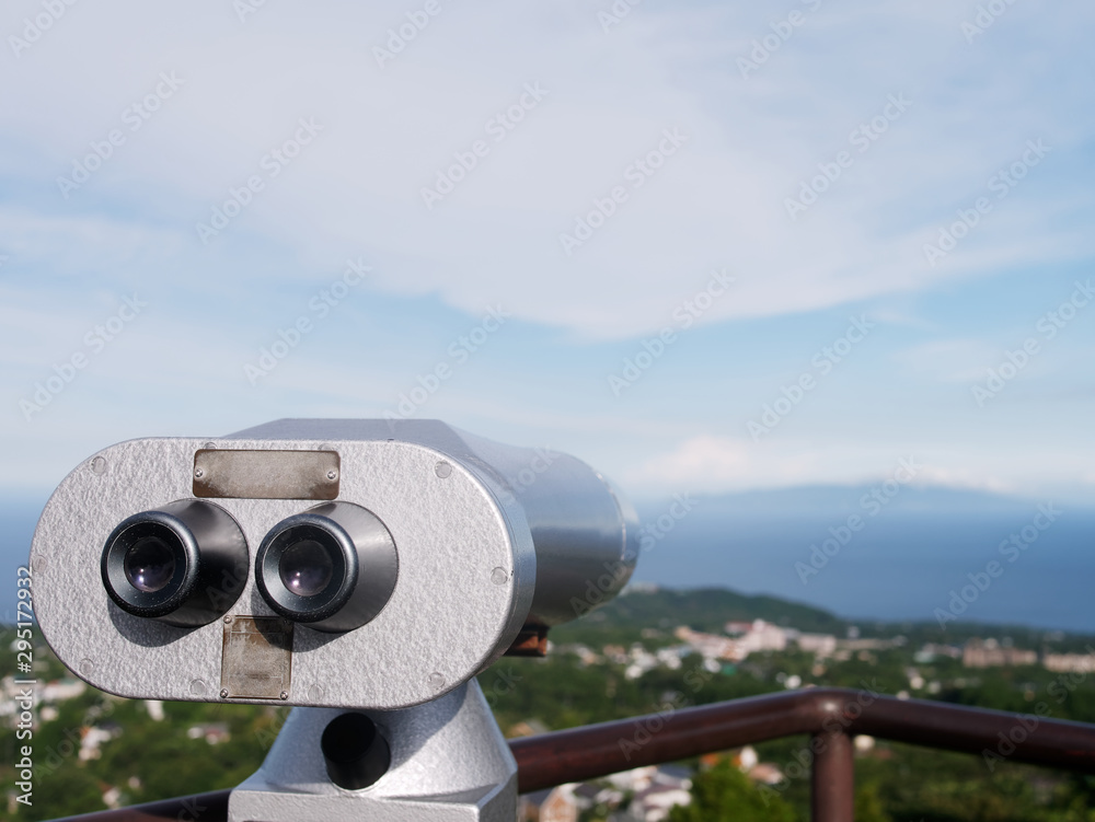Silver coin operated binoculars looking out over the coastline and the sea