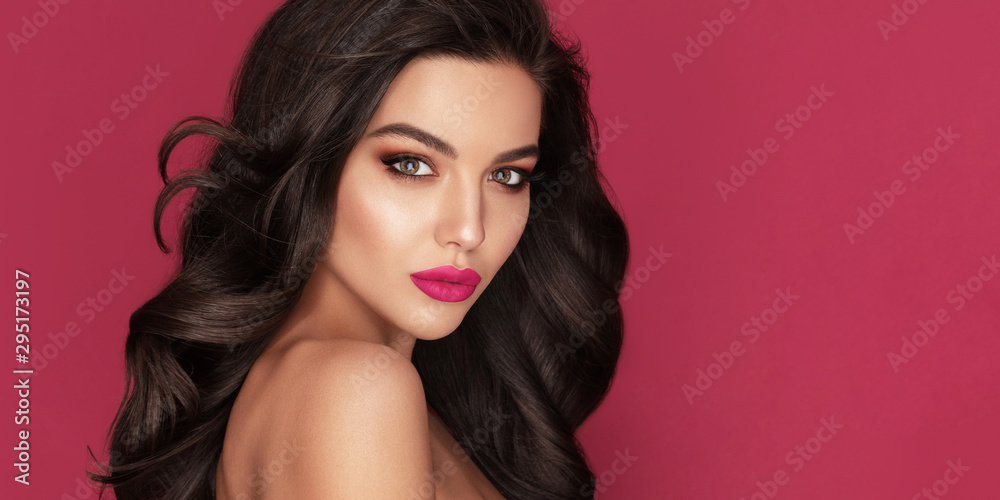 Beauty Fashion Woman Brunette Portrait with brown eyes and Healthy Long Shiny Wavy black hair. Volume shampoo. Attractive model with professional make up against red background Beauty Fashion Woman Brunette Portrait with brown eyes and Healthy Long Shiny Wavy black hair. Volume shampoo. Attractive model with professional make up against red background