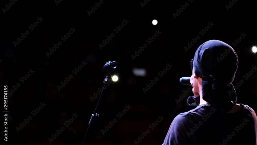 Abstract rock singer performs on stage. Selective focus. The view from the back. Blurry the auditorium with lights from mobile phones.