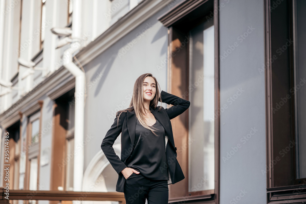 Business girl in a black suit against the background of the city