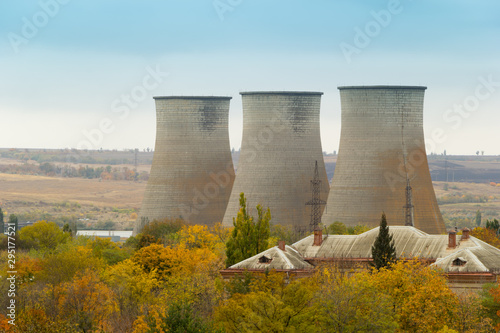 Cooling towers of a power plant. Residential buildings in the foreground. Thermoelectric plant. Overcast autumn day photo