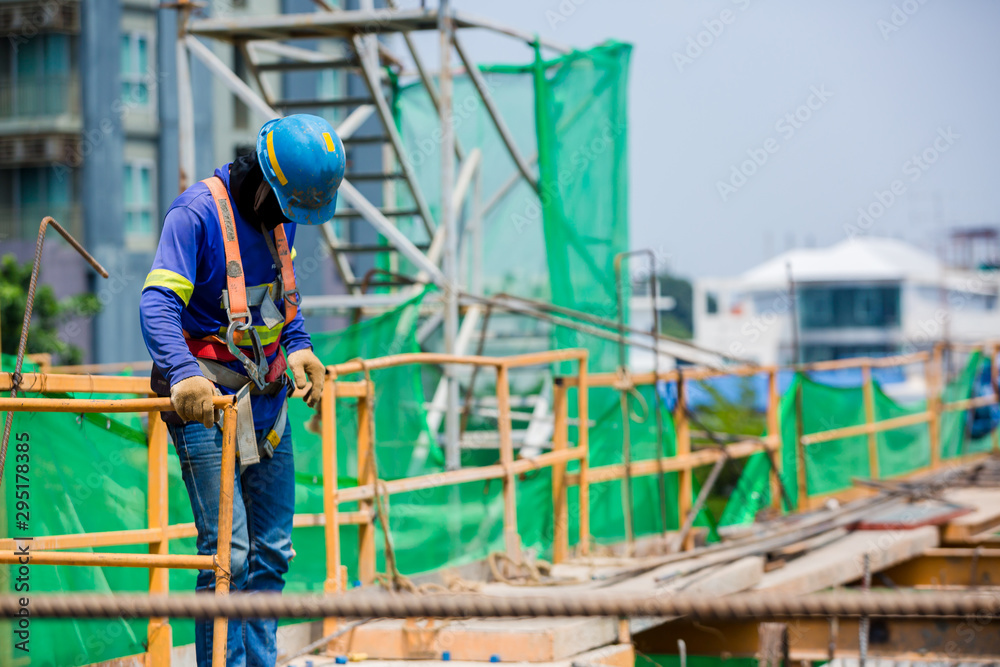 Builder worker in safety protective equipment. Professional industrial climber in helmet and uniform works at height. Risky extreme job. Industrial climbing at construction site.