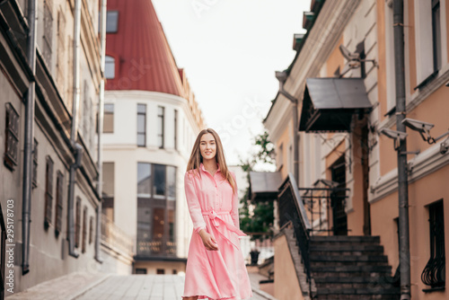 A young, beautiful girl in a pink dress walks through the beautiful streets in the city. Very beautiful portraits of a girl in the city. © majorik0207