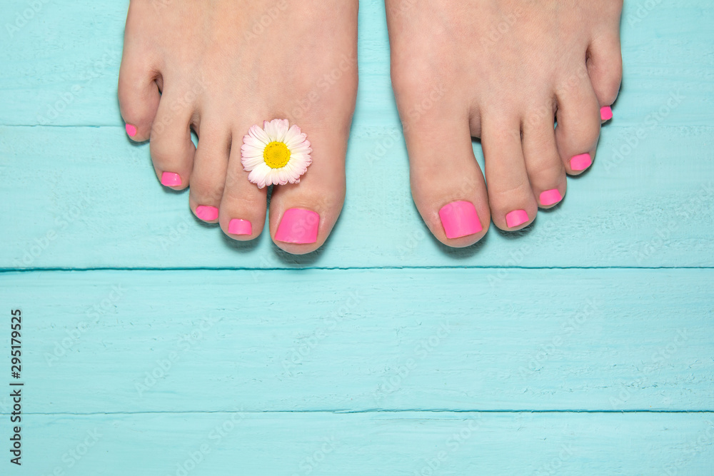 hot pink pedicure. top view of legs with pedicure. leg against the background of blue boards with a flower frame between the fingers. blue wood background hot pink pedicure. top view of legs with pedicure. leg against the background of blue boards with a flower frame between the fingers. blue wood background