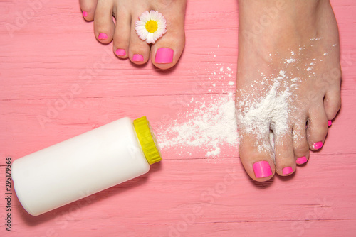 hot pink pedicure. leg against the background of a pink plank with a flower frame between the fingers. Powder for the feet with the scent of flowers. Talcum powder sprinkled on the leg.