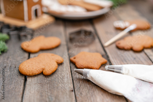 Fototapeta Naklejka Na Ścianę i Meble -  Christmas homemade gingerbread cookies on wooden table. Icing of Christmas bakery. closeup, copy space. Blank biscuit gingerbread house, ready to decorate.