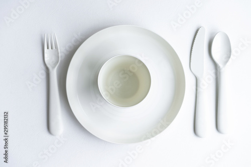 Colored bright plastic dishes beautifully laid out on a white background. Knives, forks, spoons. Menu concept for bar and restaurant. Free space for text. 