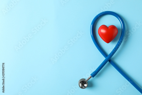 Fototapeta Naklejka Na Ścianę i Meble -  Stethoscope and heart on blue background, top view