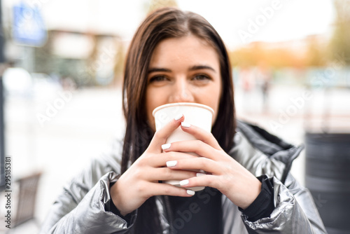 girl with pleasure drinks coffee on the street