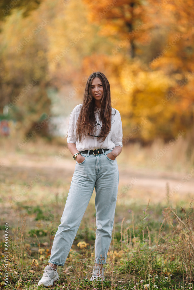 Fall concept - beautiful woman in autumn park under fall foliage Fall concept - beautiful woman in autumn park under fall foliage