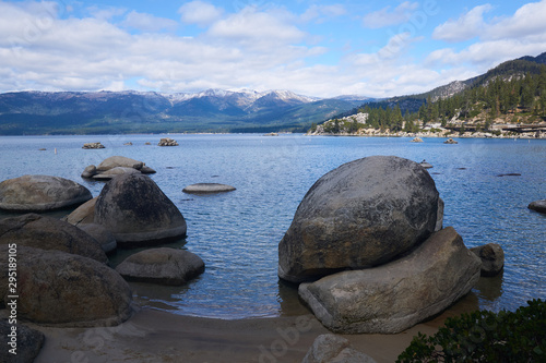 Large granite boulders on the sand beach with snow capped Sierra Mountains in the background