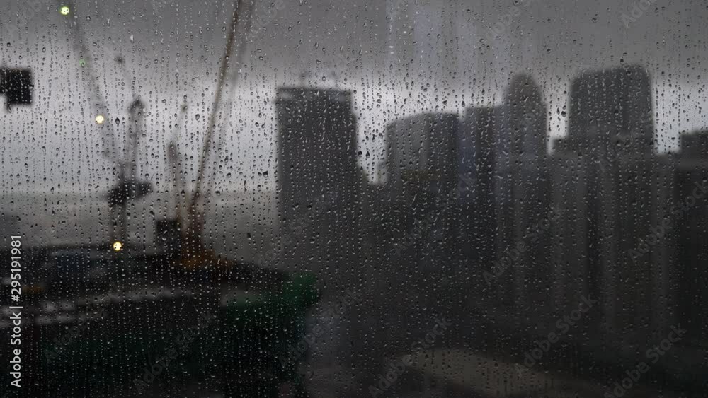 Raindrops on window glass and blurry city skyline on background
