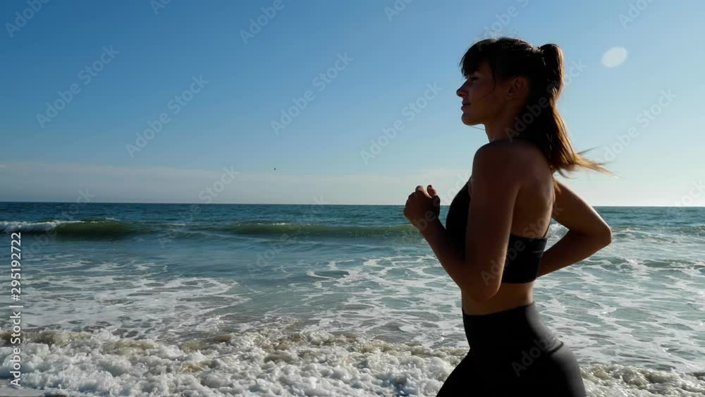 Athletic woman jogging along the beach
