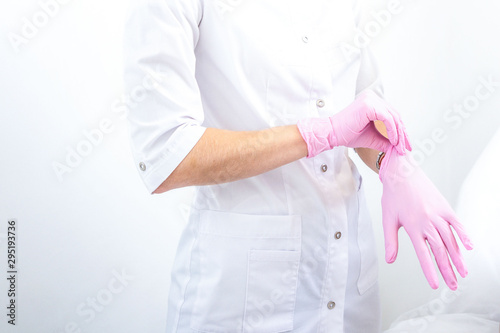 doctor puts pink rubber gloves on his hand