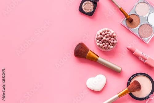 Makeup concept. Frame with decorative cosmetics and brushes on pink background top view copy space