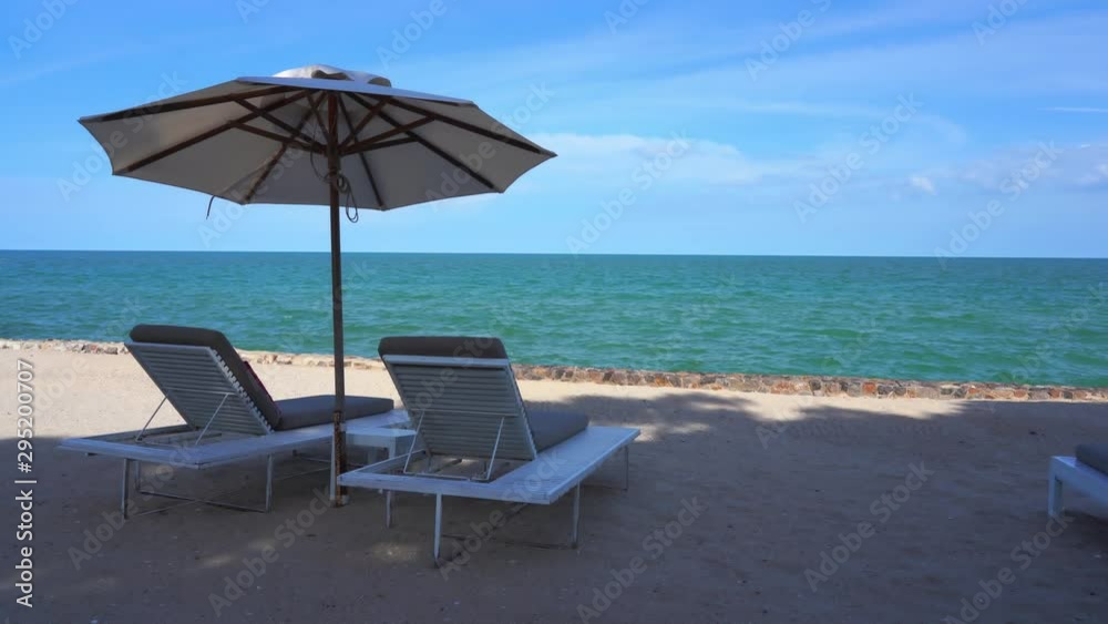 Turquoise water beyond a white sand beach with lounge chairs and an umbrella for shade. Tropical island paradise view from luxury private resort. Turquoise water beyond a white sand beach with lounge chairs and an umbrella for shade. Tropical island paradise view from luxury private resort.