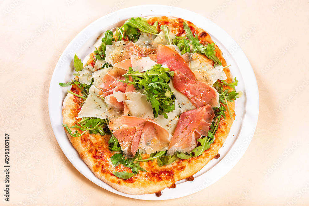 Italian Cuisine. Pizza with prosciutto, ham, arugula and parmesan Italian Cuisine. Pizza with prosciutto, ham, arugula and parmesan