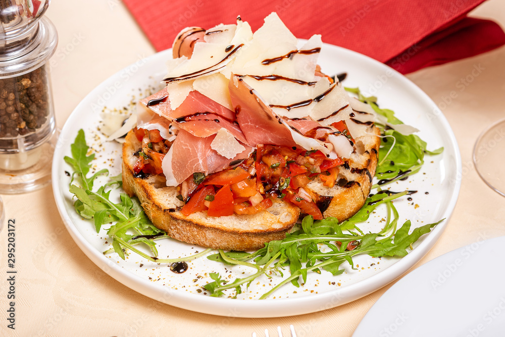 Italian Cuisine. Bruschetta with prosciutto tomatoes, ham, arugula and parmesan