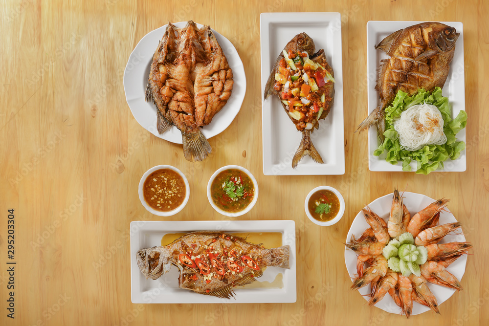 variety of thai style seafood, deep fried seabass and butterfish with spicy sauce, sweet and sour deep fried butterfish, deep fried seabass in chilli and garlic sauce and baked king prawn