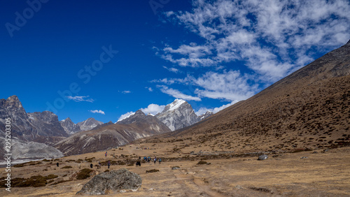 Trekkers walking through an open plain with the peaks of the Himalayas in Nepal during the Everest Base Camp trek