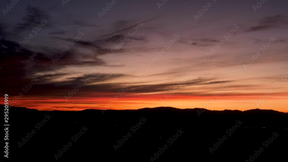 Time Lapse-Sky darkens from orange glow from setting sun as night comes over desert hills Time Lapse-Sky darkens from orange glow from setting sun as night comes over desert hills
