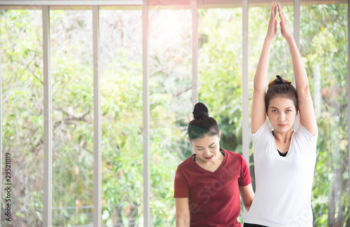 Two beautiful Asian women who are exercising, doing yoga in the room to practice their body exercises and breath control are popular concepts for body maintenance.