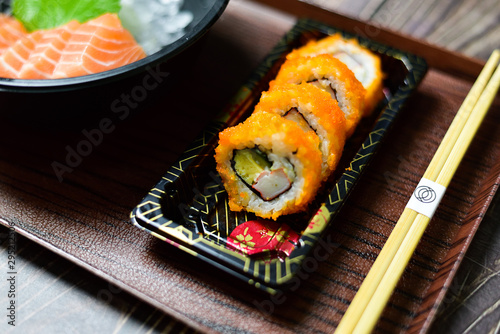 Salmon Sushi is a popular dish in Asia. Black bowl with chopsticks on the table, the concept of restaurant business. photo