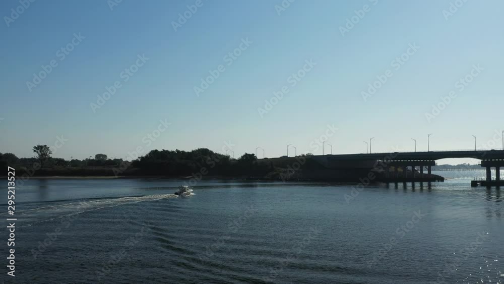 slow dramatic drone take off & flight over a small boat in Shell Bank Creek in Brooklyn, NY. The camera moves towards the Gerritsen Inlet as the sun shines on to the waters below slow dramatic drone take off & flight over a small boat in Shell Bank Creek in Brooklyn, NY. The camera moves towards the Gerritsen Inlet as the sun shines on to the waters below