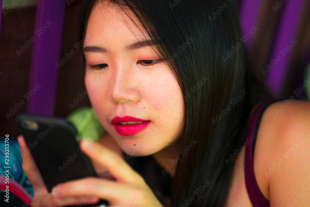 beautiful happy Asian Korean student girl using internet social media app networking with hand phone outdoors at cool cafe smiling cheerful internet dating