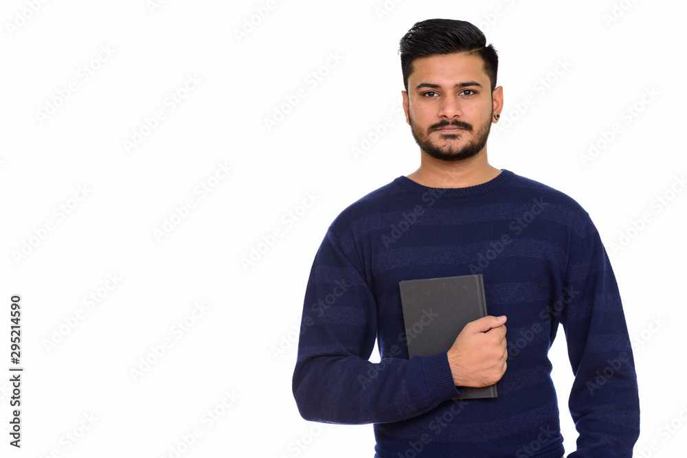 Young handsome Indian man holding book and looking at camera Young handsome Indian man holding book and looking at camera