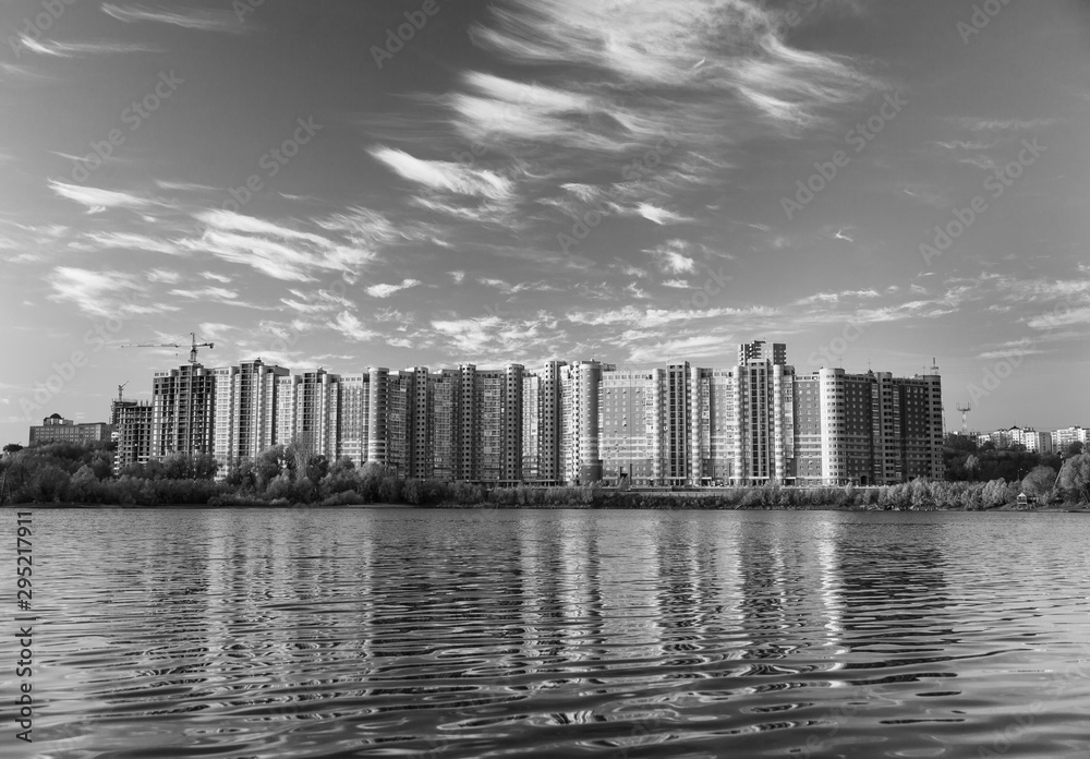 Buildings reflected in the surface of the lake against the blue sky.