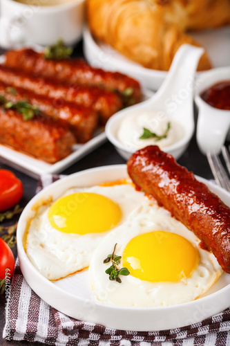 Breakfast - Fried eggs and meat sausages and sauces against a dark background. Selective focus. Copy space