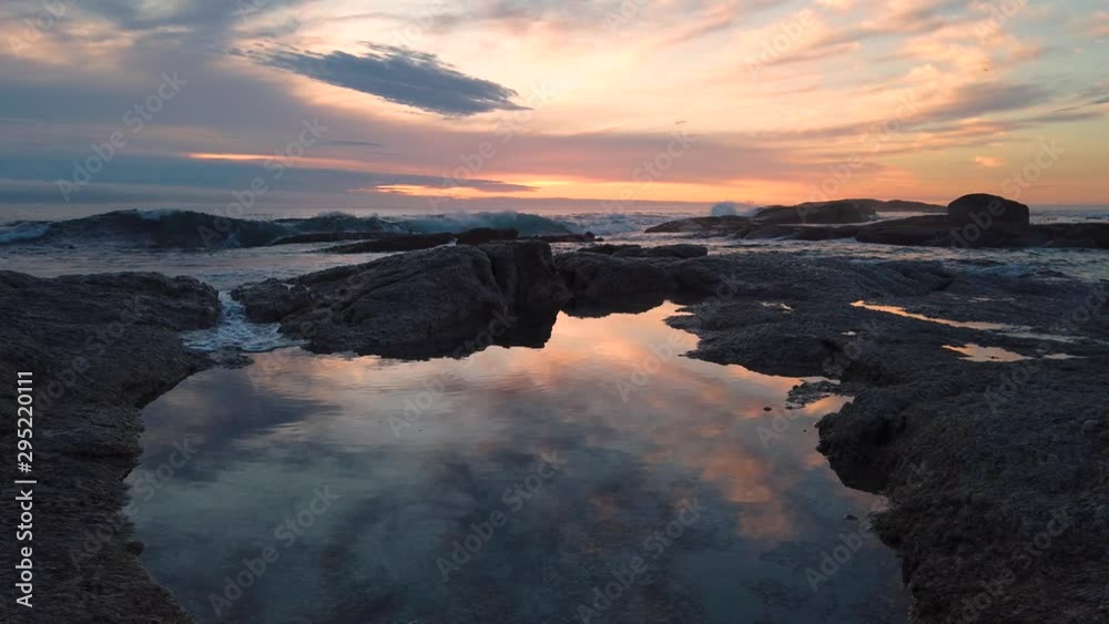 Colorful sunset over ocean as waves enter still pond by shore, slomo Colorful sunset over ocean as waves enter still pond by shore, slomo