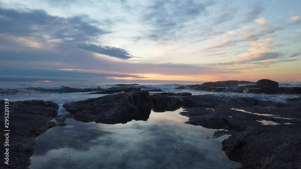 Ocean water runs into still pond as colorful sunset is reflected on surface, slomo Ocean water runs into still pond as colorful sunset is reflected on surface, slomo