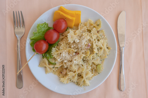 Pasta farfalle with cherry tomato and cheese in white plate, closeup