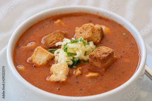 Tomato soup with croutons, cheese and fresh parsley, closeup