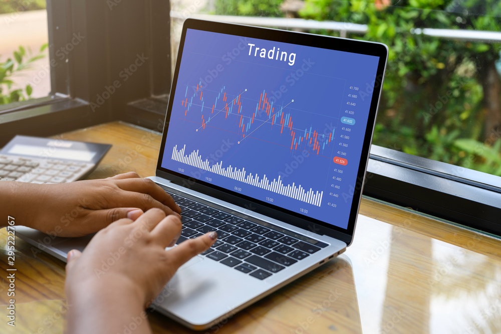 Businessman using a laptop computer with stock chart market trading on table top. mockup with clipping path for business concept. Businessman using a laptop computer with stock chart market trading on table top. mockup with clipping path for business concept.