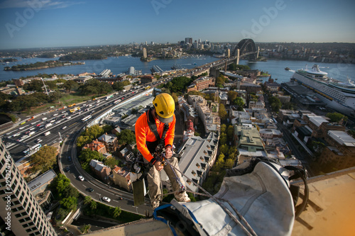 Foto Abseiler wearing full body safety harness  working at height hanging abseiling f