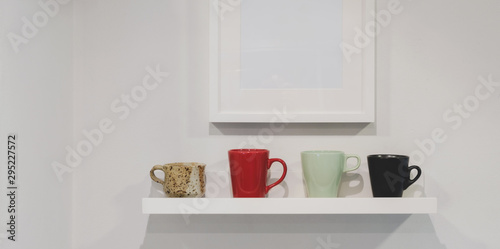 Cropped shot of wall shelf with coffee cups and mock up frame