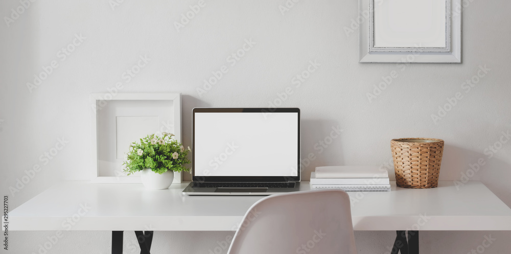Minimal workspace with open blank screen laptop computer with mock up frame and office supplies Minimal workspace with open blank screen laptop computer with mock up frame and office supplies